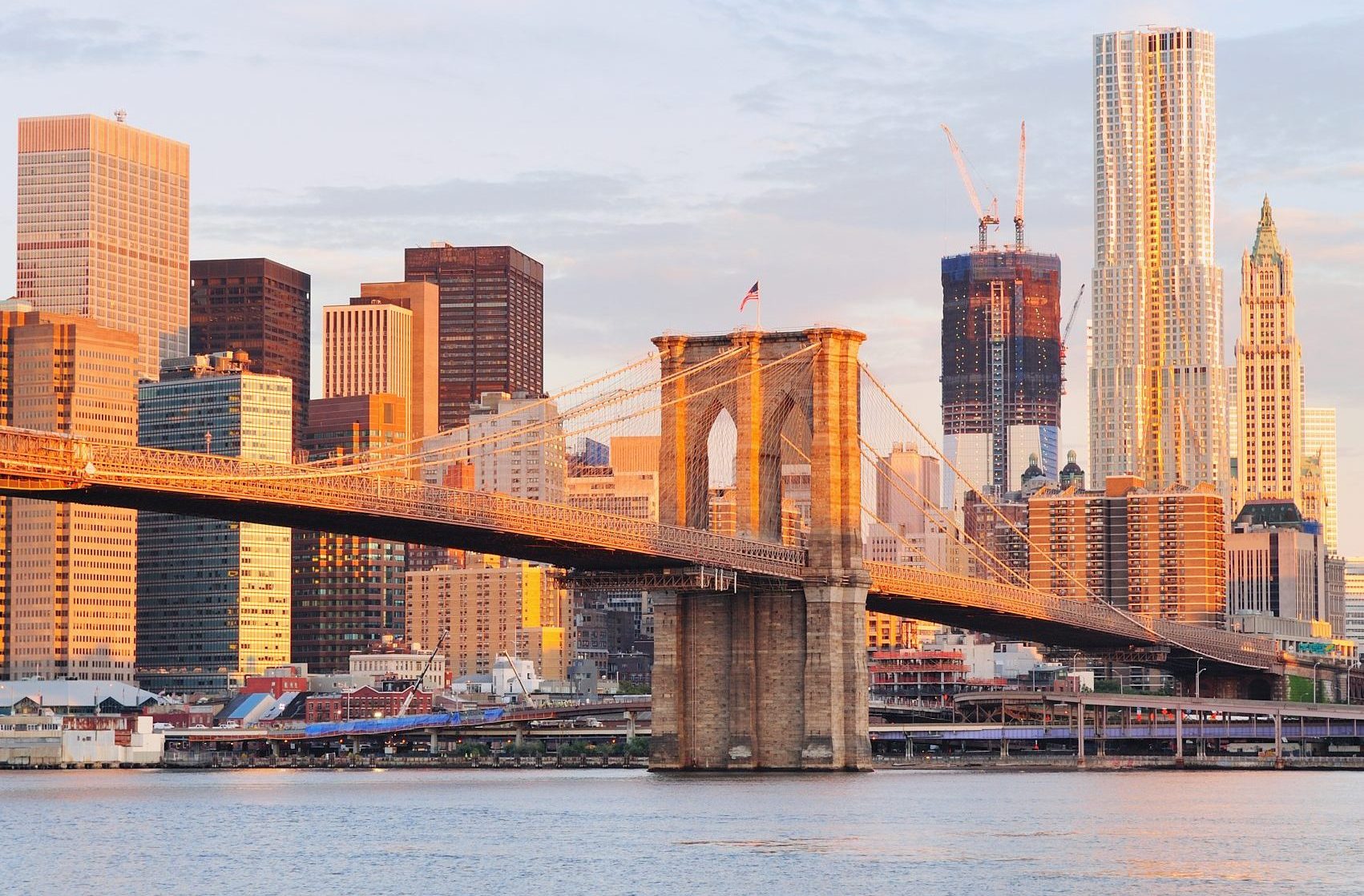 Brooklyn Bridge with lower Manhattan skyline in the morning with colorful cloud over East River in New York City